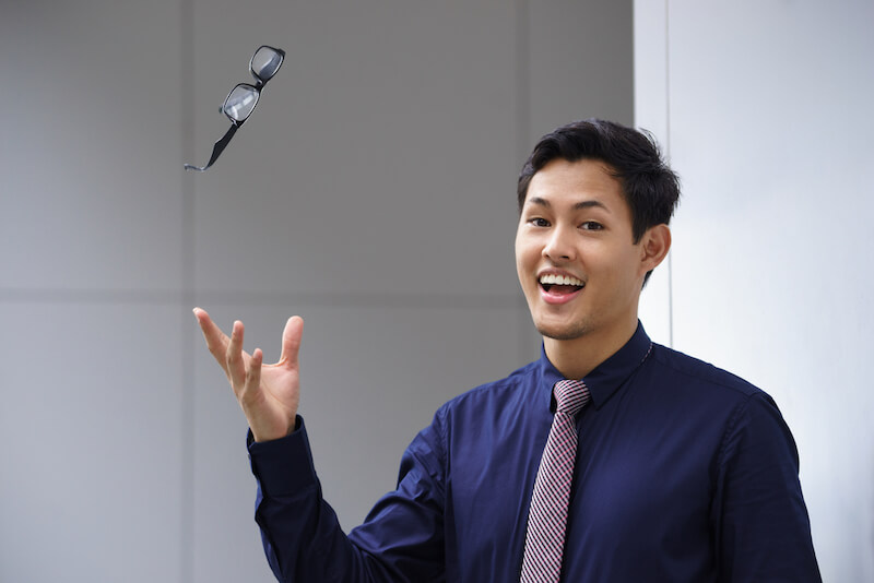 Smiling man throwing glasses up in the air.