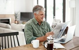 Older man at table reading newspaper