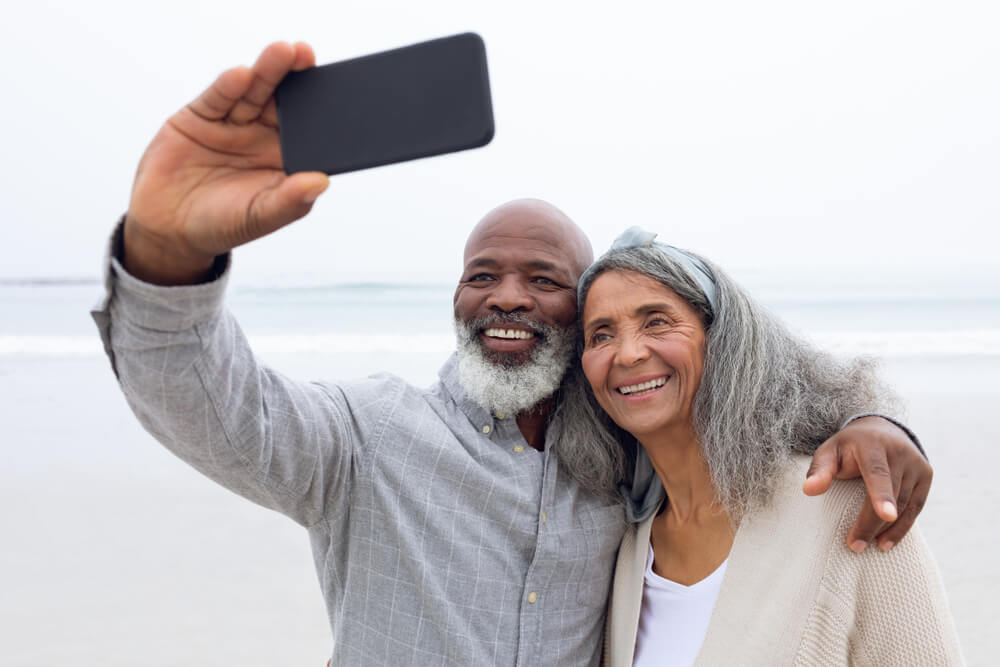 Happy senior couple taking selfie at the beach