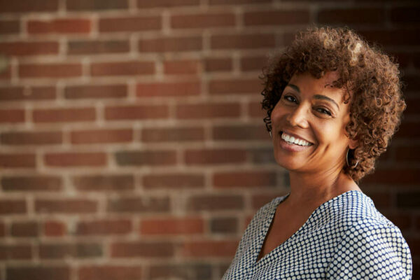 Middle-aged woman smiling in front of brick wall